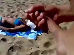 Lad jerking to unknowing wench on beach